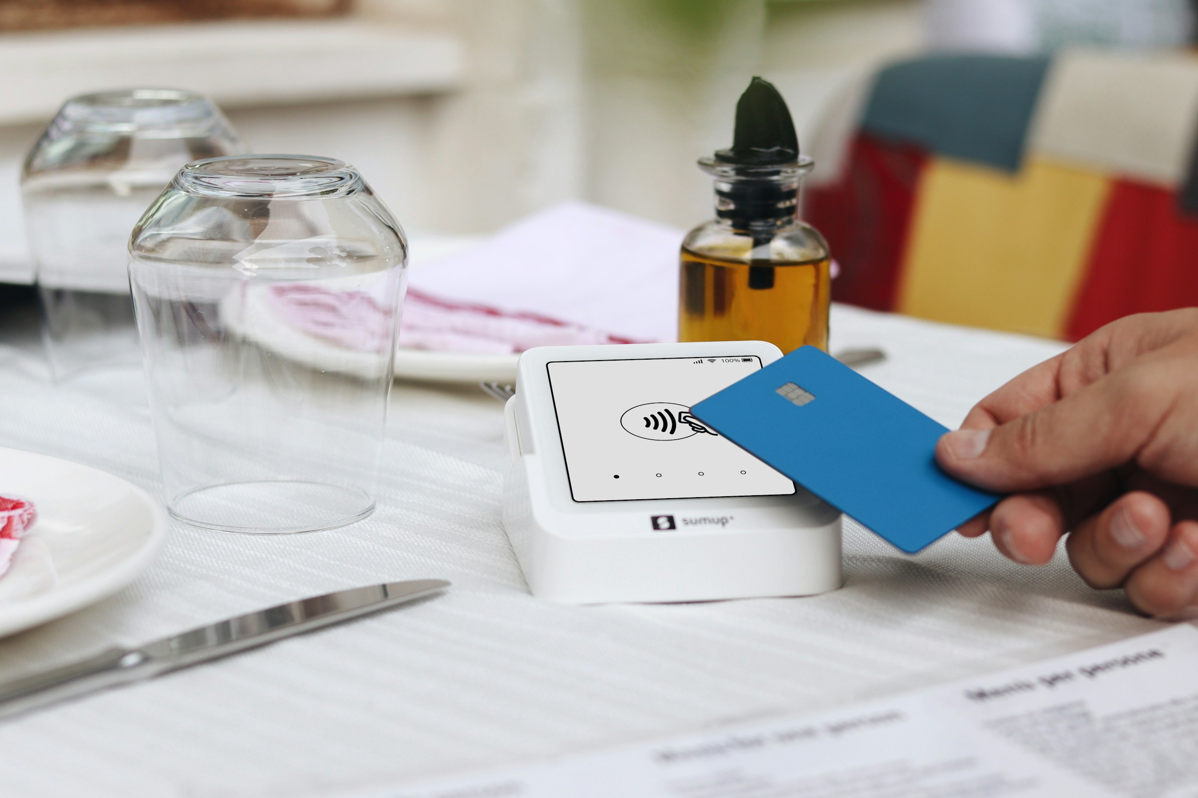 Contactless card payment at a restaurant table with a card reader